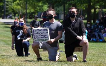 Demonstrators take a knee while the names of people who died in police custody are read during a Black Lives Matter protest.