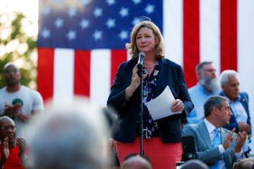 Woman speaking to a crowd in front of an american flag
