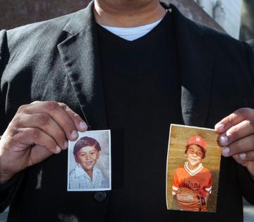 Michael Duran, a plaintiff in a sex abuse settlement with the Roman Catholic Archdiocese of Los Angeles, holds up pictures of himself when he was a child (AP Photo/Damian Dovarganes, file).  image link to story