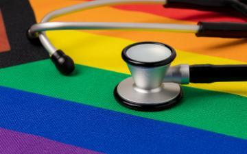 Rainbow pride flag and stethoscope. Transgender and LGBTQ+ healthcare and mental health concept. Photo By JJ Gouin_Adobe Stock.
