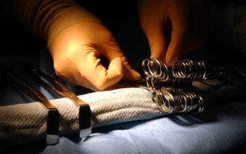 hands wearing surgical gloves organizing surgical tools