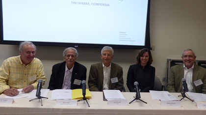 Panelists seated at a table beneath a screen displaying 'executiveCompensation' title.