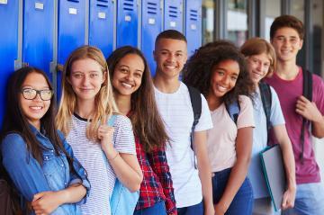 High school students smiling and standing near lockers.