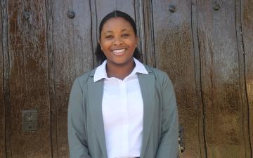 A person smiling in front of a wooden wall. image link to story