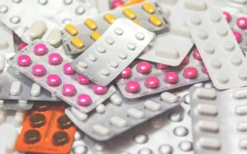 A pile of generic tablet and capsule medication in pre-packaged foil cards.