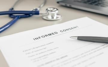 Informed Consent form on doctor desk. Photo By Andres Victorero_Wirestock Creator_Adobe Stock.