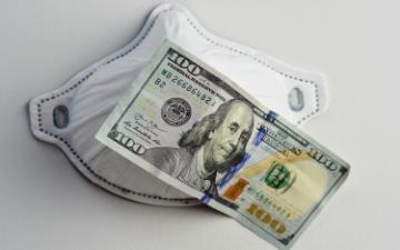 A surgical mask with a US 100 dollar bill placed on it.