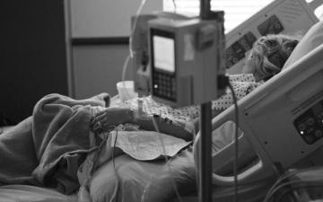 Woman laying on a hospital bed connected to IV and heart rate monitor.