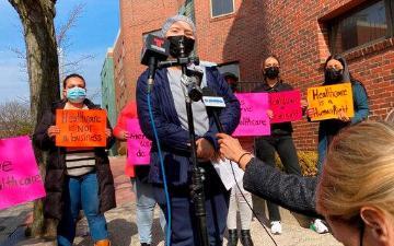 A woman who identified herself only as Jasmin, 19, of Revere, Mass., front top, speaks to reporters about her experience at East Boston Neighborhood Health Center during a news conference, Tuesday, March 15, 2022, in front of the Boston health clinic, in the East Boston neighborhood of Boston. AP Photo/Philip Marcelo