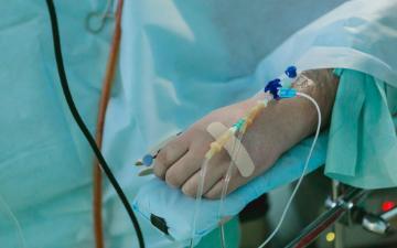 Patient on operating table with IV connected to left hand. Photo by Olga Kononenko on Unsplash
