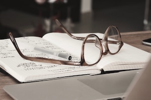 Glasses with grey frames on top of a notebook 