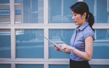 A woman dressed professionally examining contents on an iPad image link to story