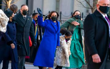 Vice President Kamala Harris in a blue coat with others, all wearing masks. image link to story