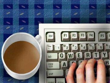 A hand typing on a keyboard next to a cup of coffee. image link to story