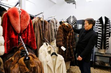 Person browsing fur coats in a store labeled Fur Ban. image link to story