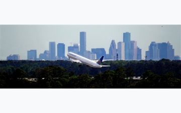 A plane takes off in front of the Houston, TX skyline. (AP Photo/David J. Phillip)