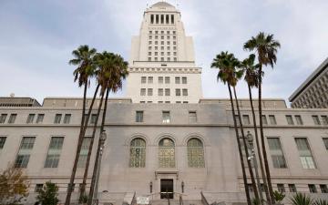 Los Angeles City Hall with palm trees in the foreground. image link to story