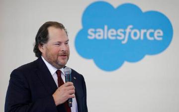Man holding microphone in front of Salesforce logo. image link to story