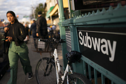 Pedestrians pass the 36th Street subway station where a shooting attack occurred the previous day during the morning commute, Wednesday, April 13, 2022, in New York.  (AP Photo/John Minchillo)