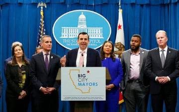 Group of seven people standing behind a podium with City of San José logo. image link to story