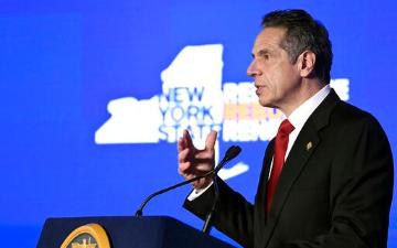 Andrew Cuomo giving a speech against a New York state outline background. image link to story