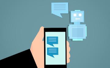 A hand holding a smartphone that displays a chatbot conversation. image link to story