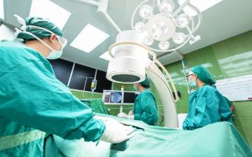 Healthcare workers wearing green scrubs performing surgery in an operating room. image link to story