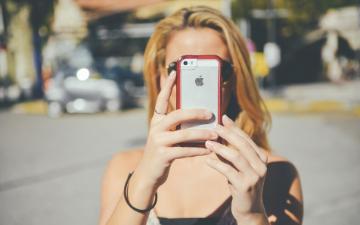 woman holding iPhone to take a photo image link to story