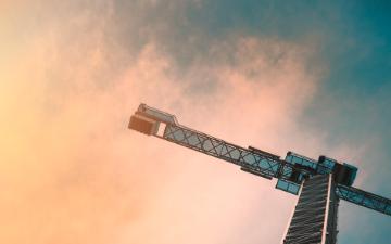 Skyscraper construction site with a crane against a cloudy sky. image link to story