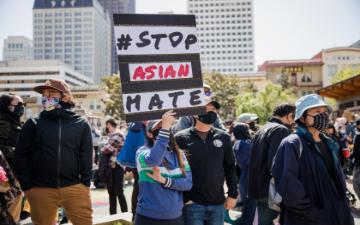 People at a rally holding a sign that says We Stand United Against Hate. image link to story