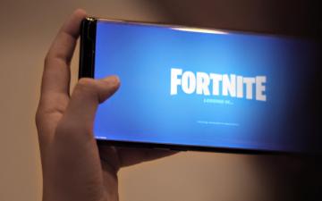 Person holding a phone displaying the Fortnite game loading screen. image link to story