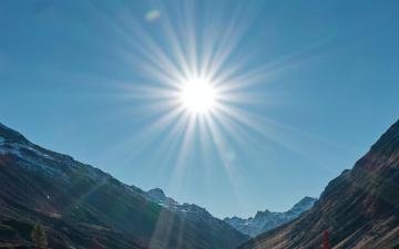 A straight road under the bright sun with mountainous scenery. image link to story