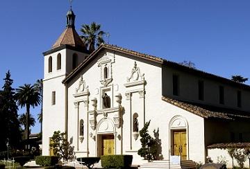 A white mission-style church with a tower under a clear blue sky. image link to story