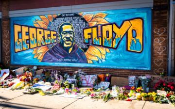 Mural with Floyd and a memorial site with flowers. image link to story