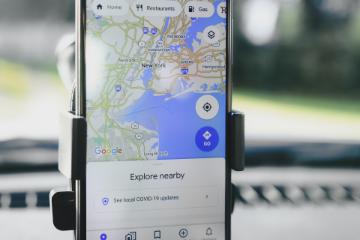 A phone with Google Maps open, attached to the dashboard of a car.