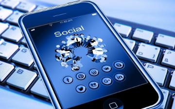 A smartphone showing social media icons on top of a keyboard. image link to story