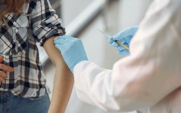 A healthcare professional administering a vaccine to a person. image link to story