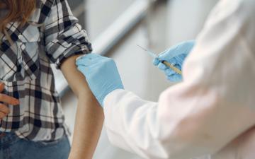 A medical professional administers a vaccine injection to a patient. image link to story