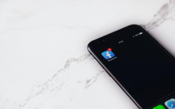 A smartphone displaying the Facebook app icon on a marble surface. image link to story