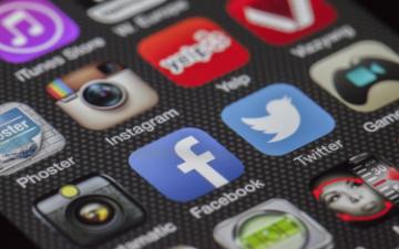 Close-up of social media app icons including Twitter and Facebook on a smartphone screen. image link to story