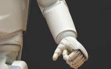 AI robot hand with white and gray components pointing forward. image link to story