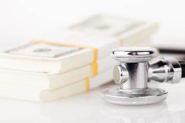 Stethoscope next to stacks of hundred dollar bills. image link to story