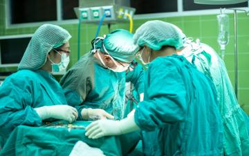 Surgeons performing an operation in an operating room. image link to story