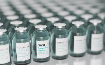 Rows of vaccine bottles with labels and green caps. image link to story