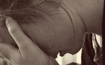 A woman holding her head, appearing to cry. image link to story
