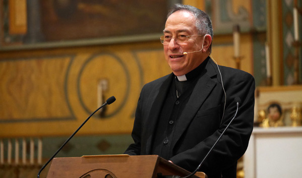 A priest speaking at a podium inside a church.