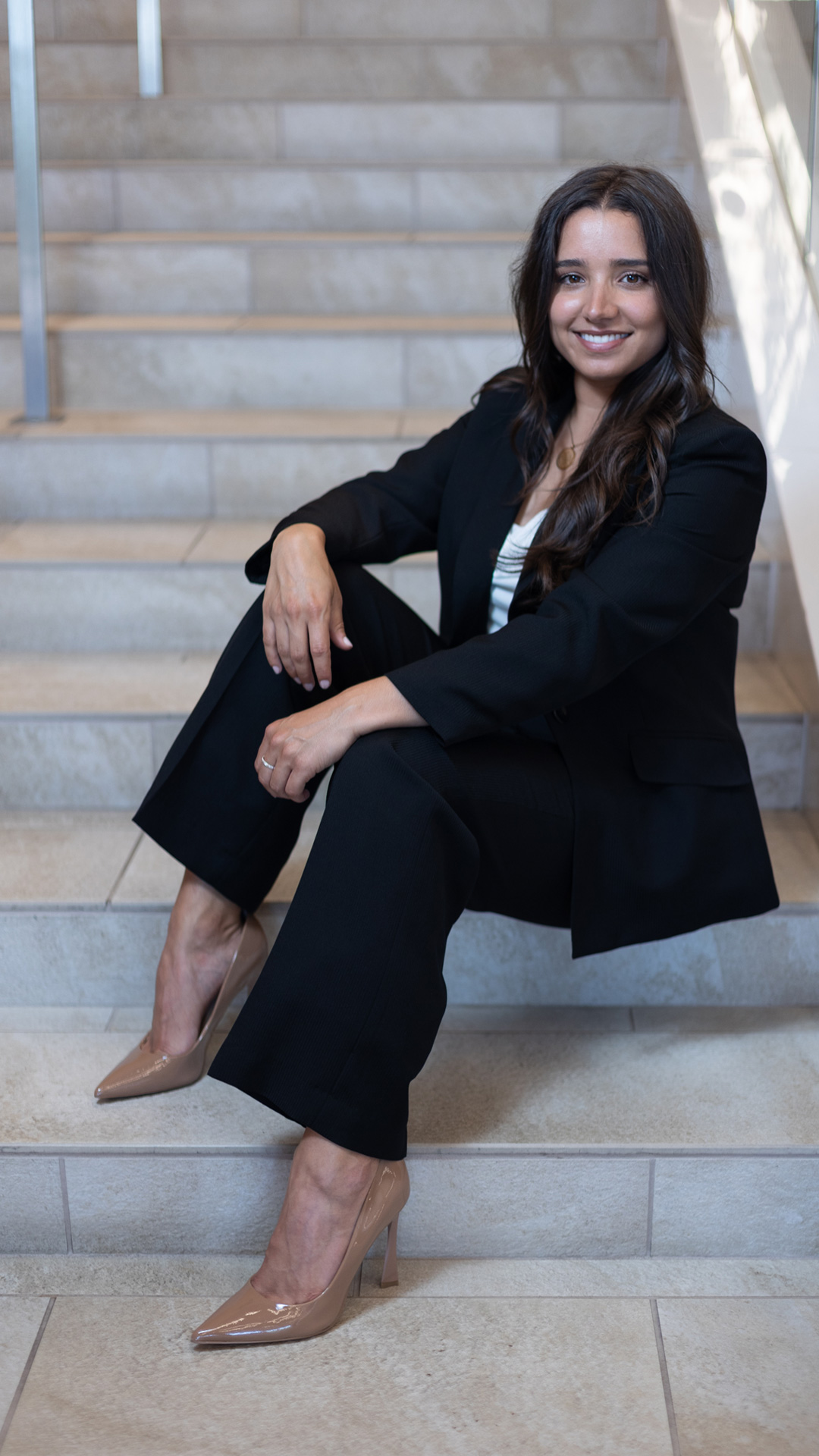 Mirelle Raza '15 is seated on a step at the bottom of a staircase.