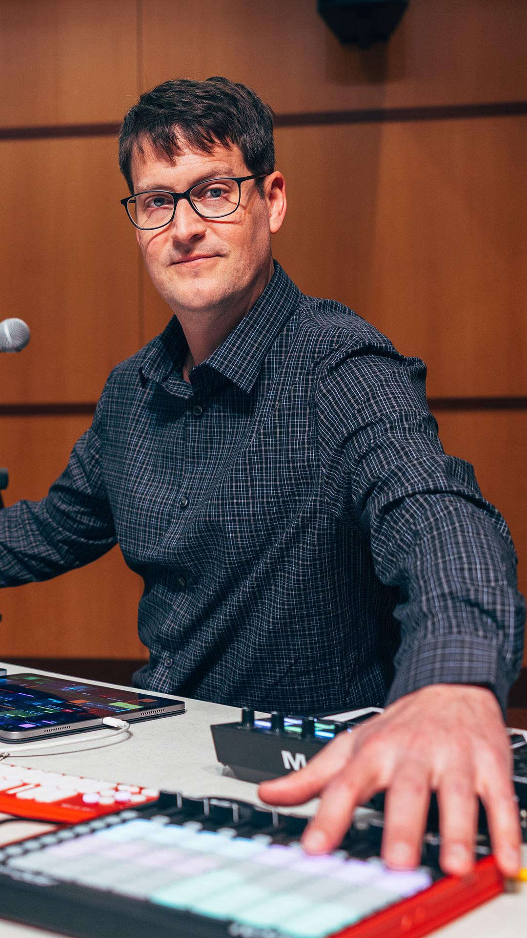 Sam Pluta sits at a table with electronic devices on it.