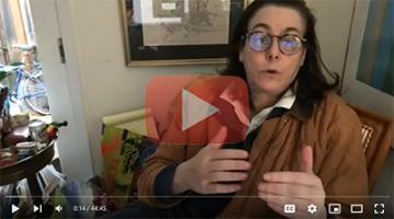 A person wearing glasses speaking in a decorated room.