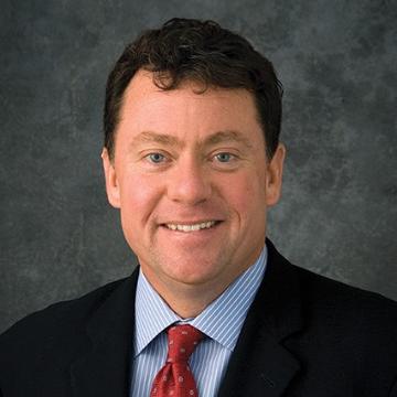 Man in a suit and tie against a dark background.